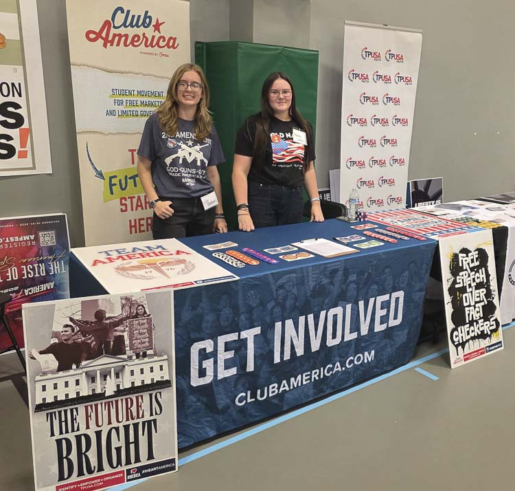 Lily Johnson and Ashley Ireton volunteered Tuesday to work the table for Club American, Turning Point USA’s brand directed at high school students. Photo by Paul Valencia