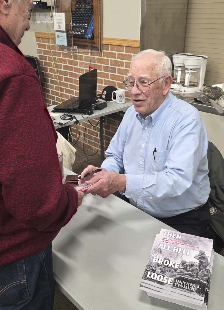 Dennis Fisher thanks a fellow veteran who bought Fisher’s book at the Community Military Appreciation Committee breakfast last week. Photo by Paul Valencia