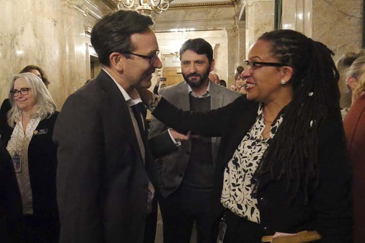 Gov. Bob Ferguson, left, and House Finance Chair April Berg, D-Mill Creek, right, celebrate in the Democratic wings of the House after Democrats' bill to impose an income tax on millionaire earners won House approval on March 10, 2026. At center is Shane Esquibel, Ferguson’s chief of staff. Photo courtesy Bill Lucia/Washington State Standard
