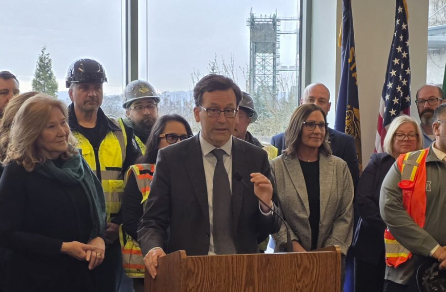 Washington Governor Bob Ferguson, with the mayor of Vancouver Anne McEnerny-Ogle on his right and the Interstate Bridge in the background, outlines his vision for the immediate future of the replacement bridge project. Photo by Paul Valencia