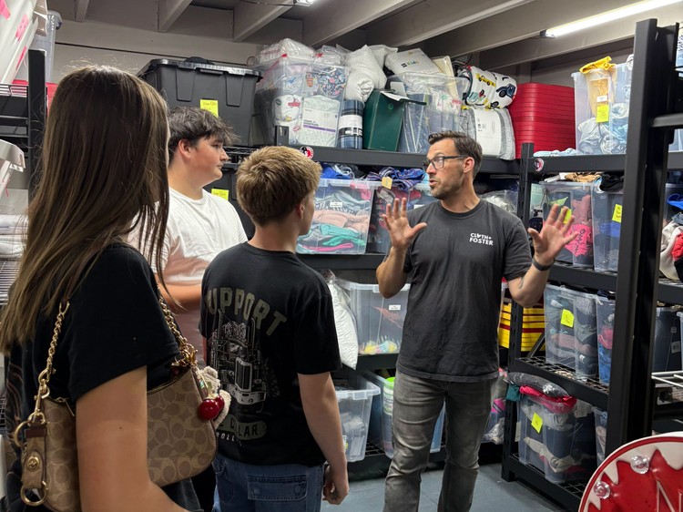 Aric Clapp, co-founder of Cloth and Foster, gives a tour of the nonprofit organization’s warehouse to students from Skyview High School who had dropped off a donation. Photo by Mindy Williams Cleeland