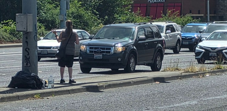 The person standing on this traffic island on Thursday, June 18, likely has not heard about the new ordinance passed by the city of Vancouver, banning the practice. The city council voted Monday to give law enforcement tools to require people to move along to a safer location