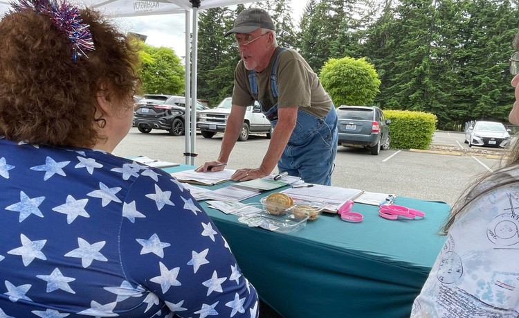 Doug Hicks signs an initiative petition on June 3, 2026 in Tumwater, Washington. The proposed ballot measure would repeal a statewide income tax on high earners enacted earlier this year.