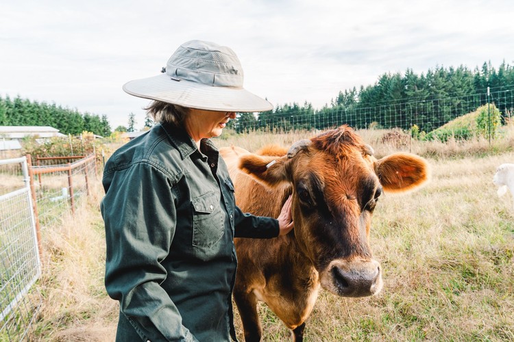 Owner and operator of April Joy Farm, April Thatcher, stands with one of her cows on the farm.