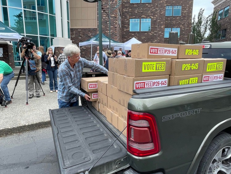 A volunteer for Let’s Go Washington unloads boxes of petitions for Initiative 645 that were turned in to the secretary of state’s office on July 2, 2026. The measure to repeal Washington’s new income tax was certified for the November ballot on Wednesday.